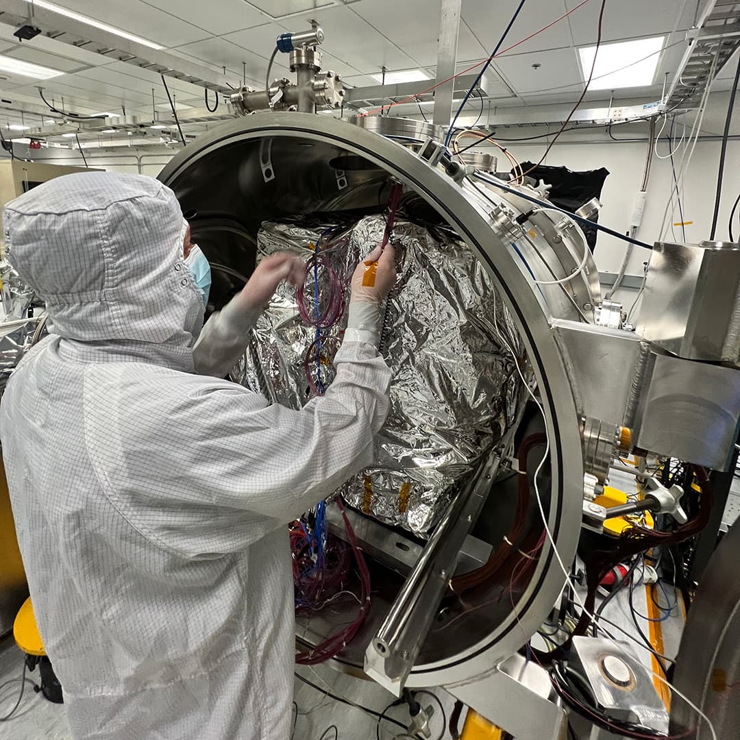 An engineer prepares the imaging spectrometer instrument for testing in a thermal vacuum chamber at JPL